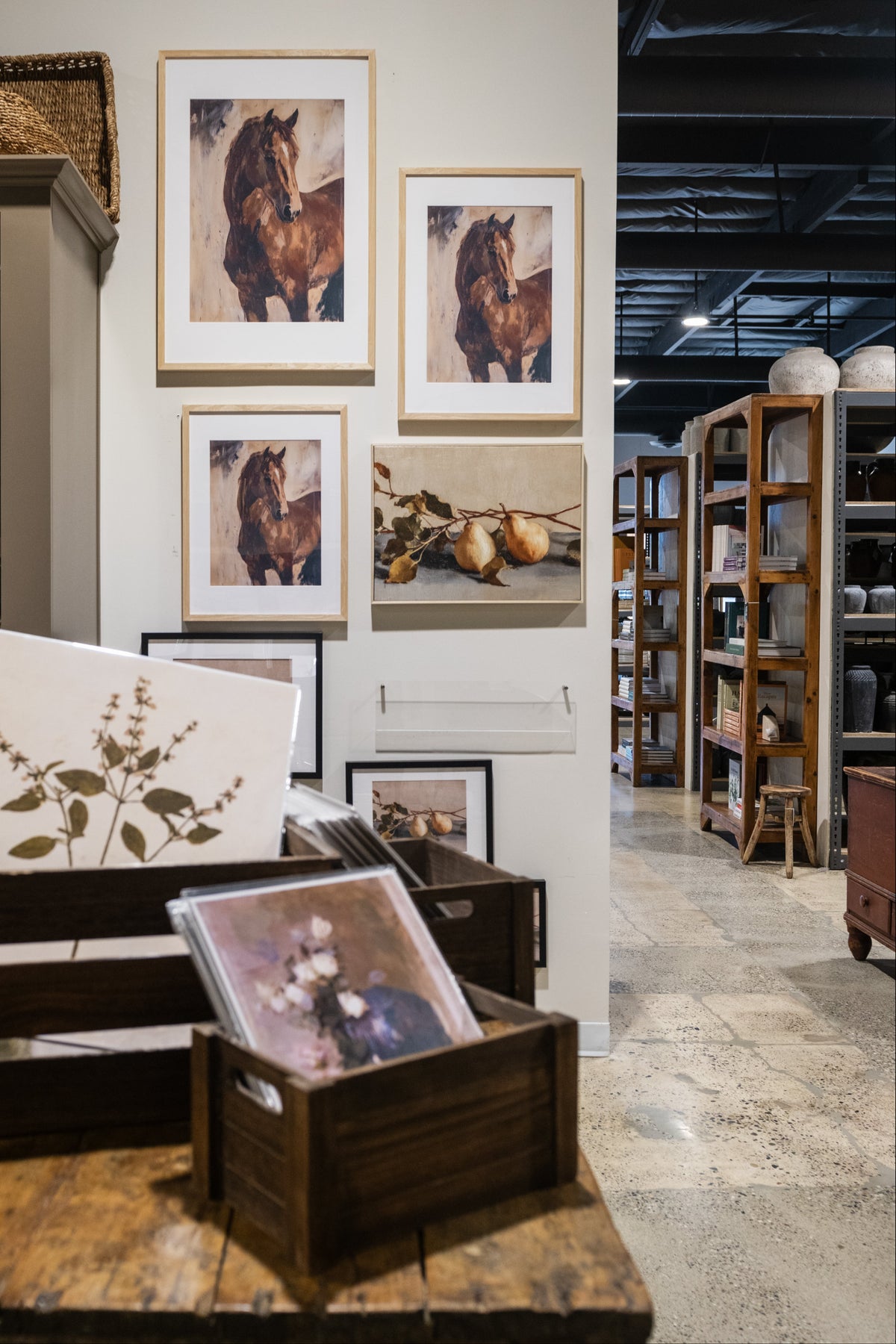 Framed pictures and artwork displayed on a table in a store setting.